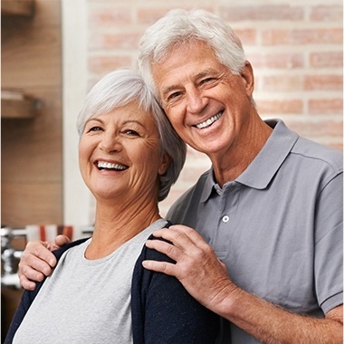 Older man and woman smiling and hugging